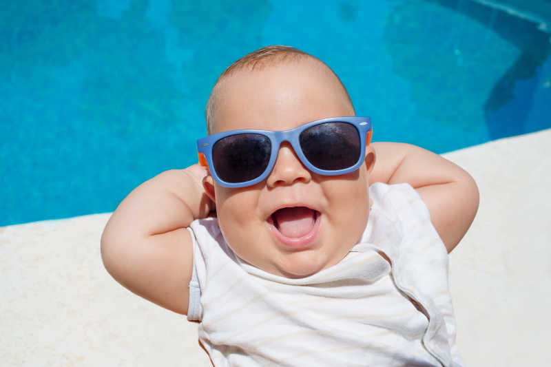 游泳池旁戴着墨镜大笑的婴儿