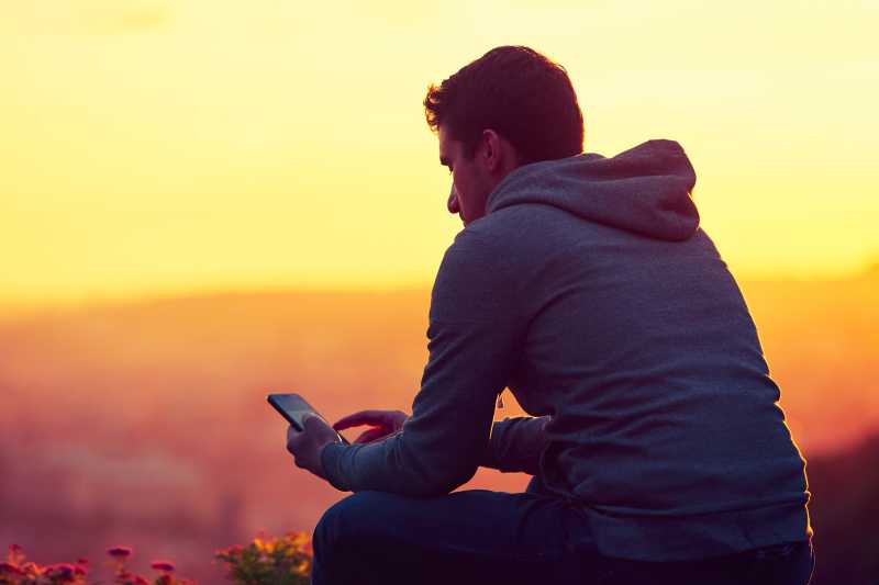 一个男人拿着手机在夕阳下