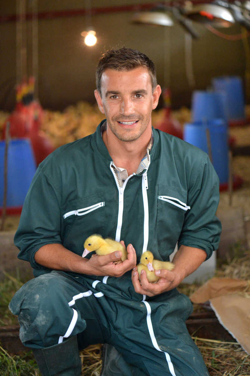 快乐的农民和他怀里抱着两只刚出生的小鸭