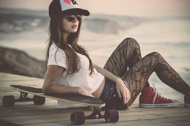 时尚的年轻女子与一个滑板