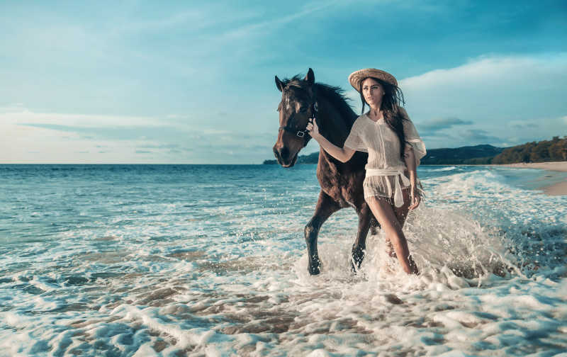 牵着马在海边散步的女人
