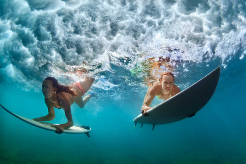 冲浪女选手拿着冲浪板跳水
