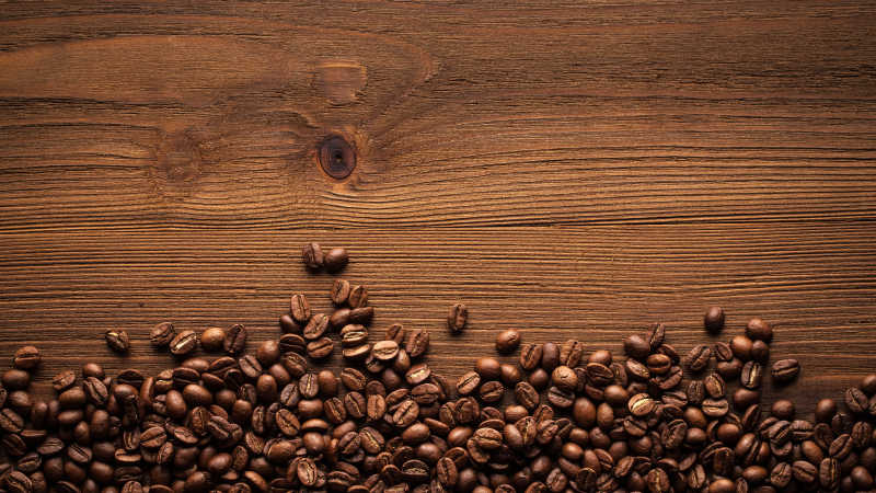 咖啡豆洒在棕色木桌上