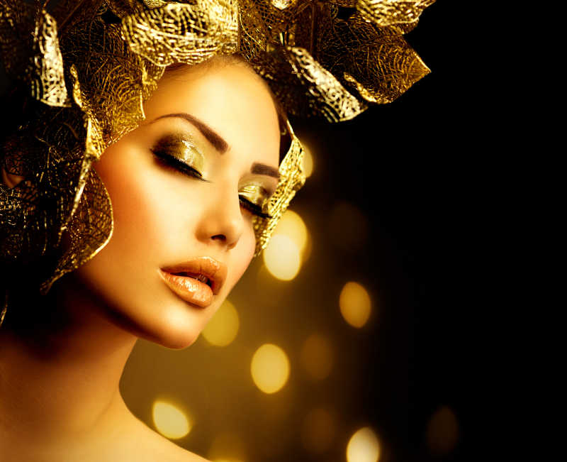 画着金妆的女人闭着眼头上戴着金色的饰品