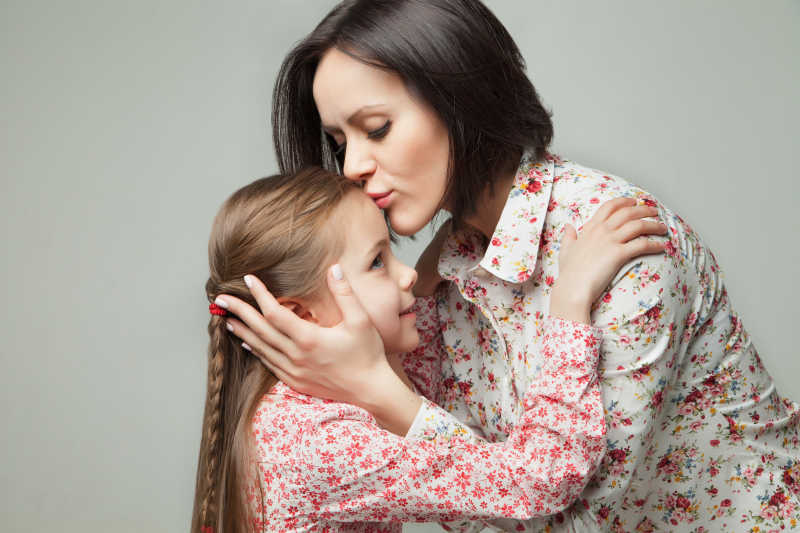 美丽年轻的母亲亲吻她的女儿