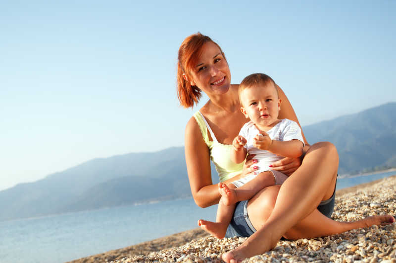 海滩边婴儿坐在母亲的腿上