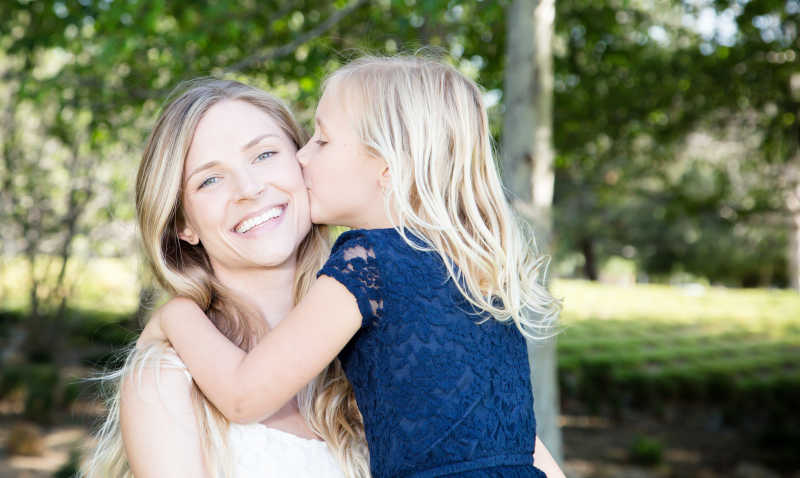 女儿在公园亲吻她的母亲