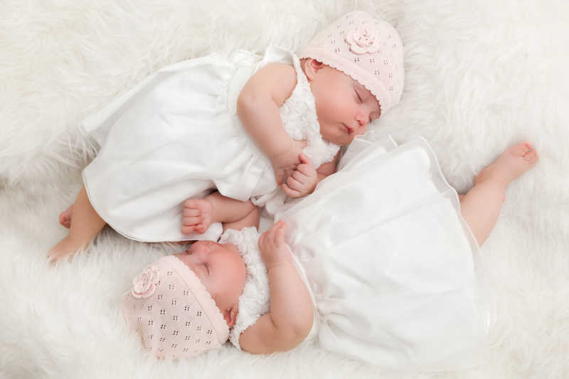 在毯子上睡觉的可爱的双胞胎姐妹