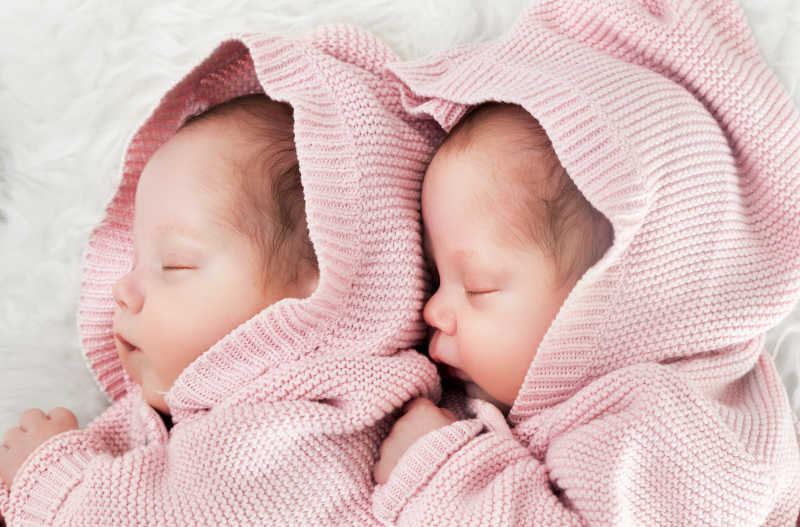 新生双胞胎姐妹睡在白色的毛皮上