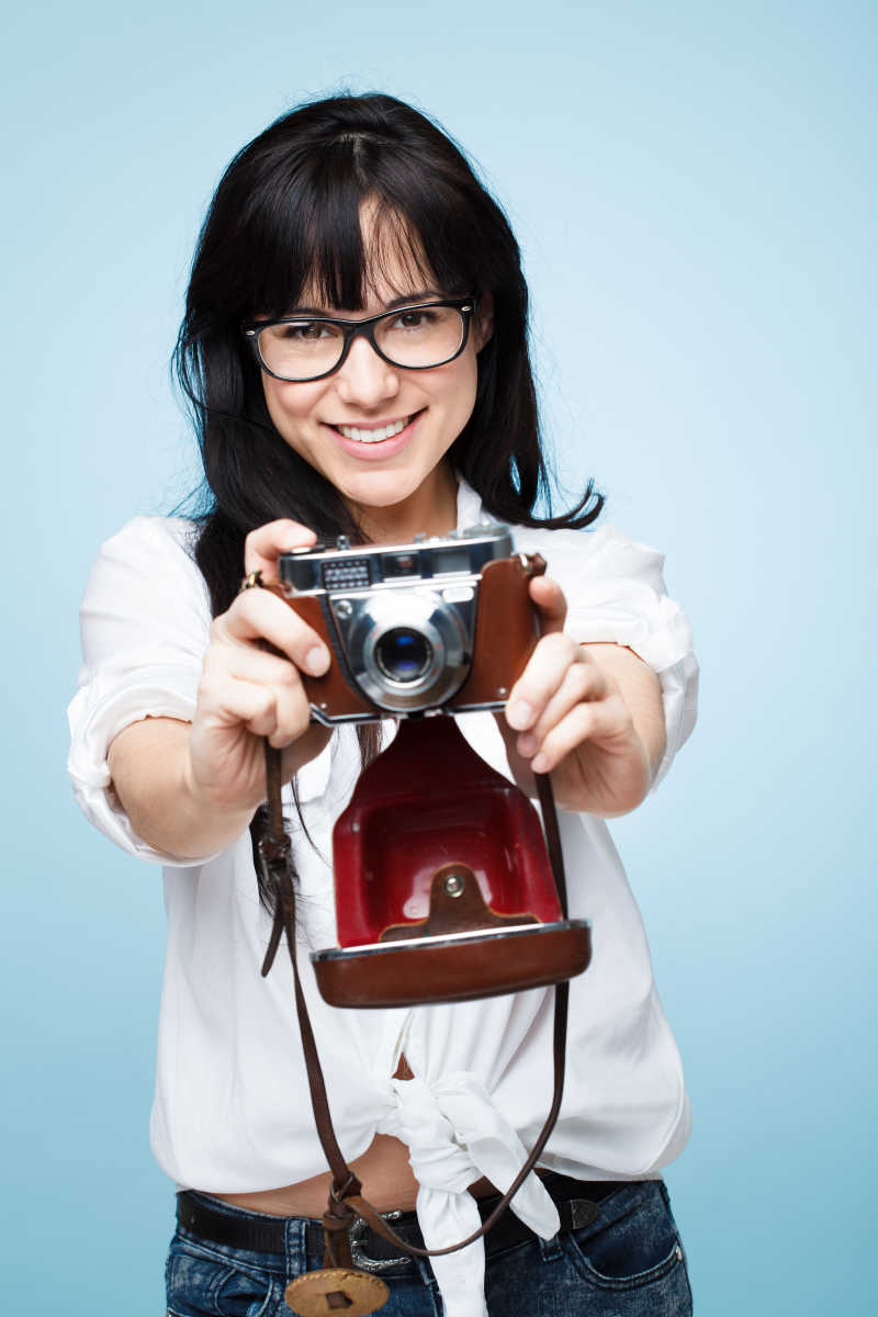 可爱的年轻女摄影师拿着相机是一个时髦rretro