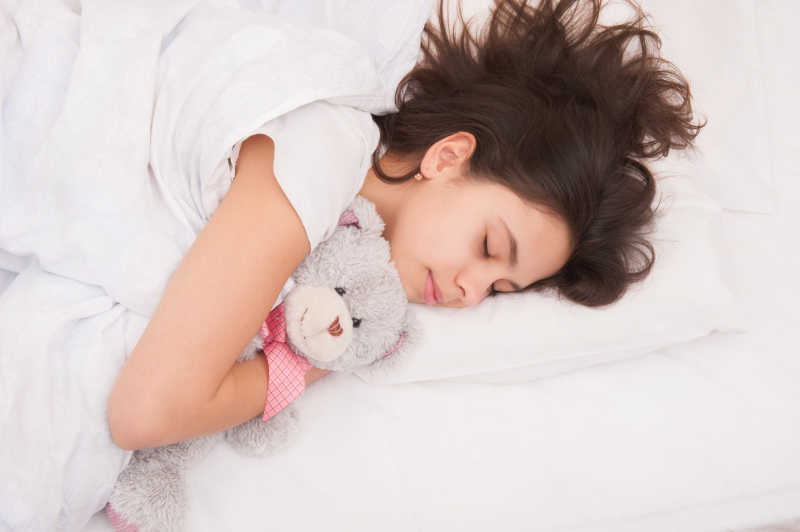 女孩睡在床上抱着泰迪熊