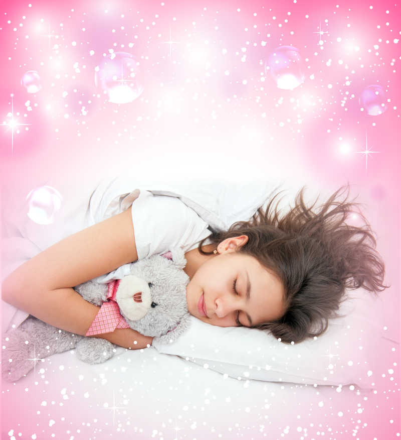 粉红色的背景下女孩抱着泰迪熊睡觉