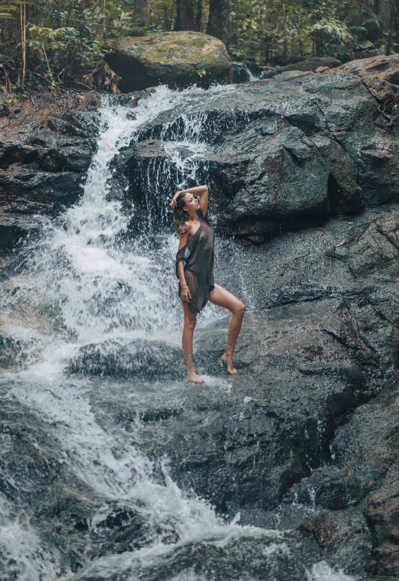 性感的女人在瀑布上摆姿势