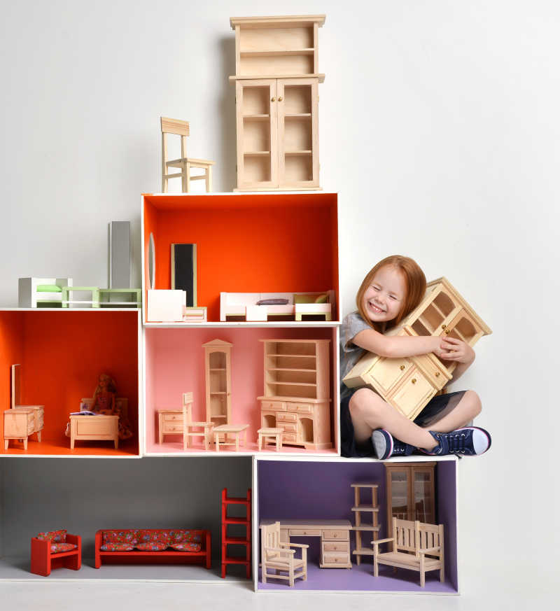 棕色头发儿童坐在小型积木玩具上怀里抱着小型衣柜积木