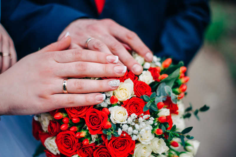 新婚夫妇戴着戒指的手放在捧花上