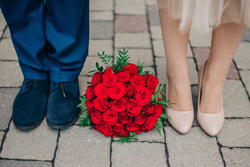 新婚夫妇脚之间的红玫瑰捧花