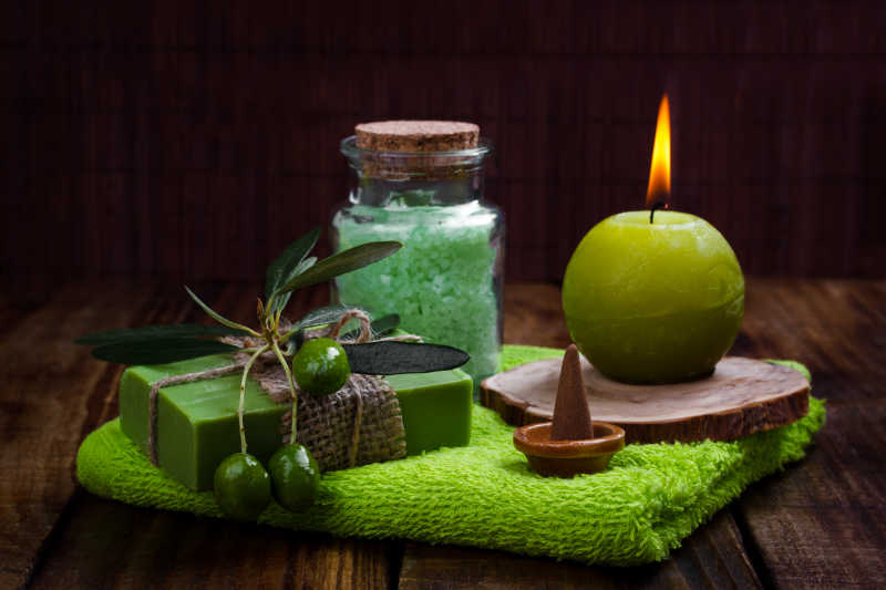 绿色毛巾上的手工橄榄肥皂蜡烛和浴盐