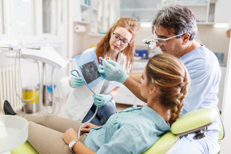 高级男牙医在牙科诊所与女病人交谈和准备治疗