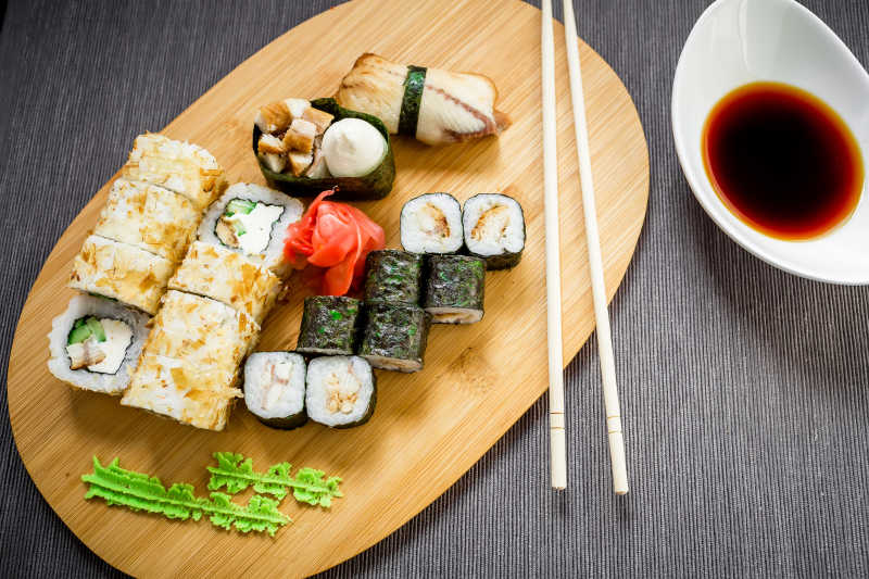 在灰色的背景传统的寿司卷酱油和筷子