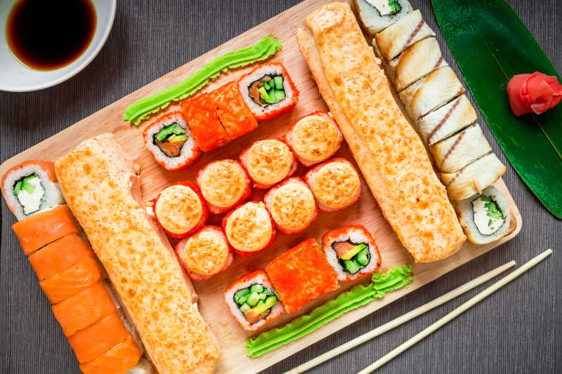 灰色背景下亚洲著名寿司卷酱油和筷子