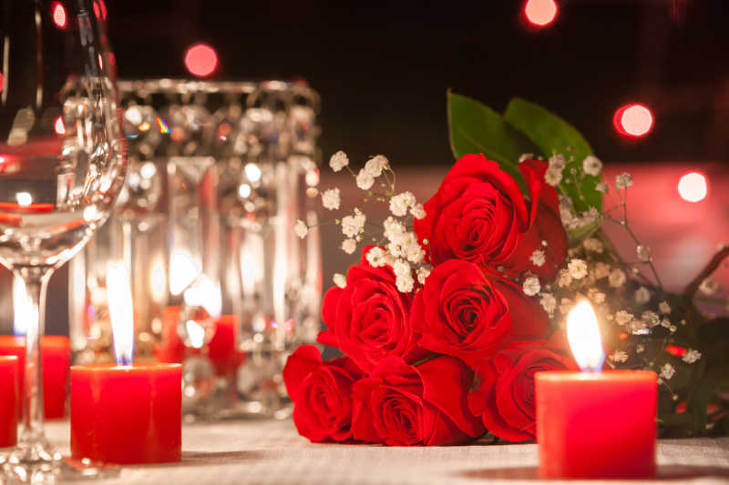 蜡烛灯包围桌上的红玫瑰浪漫之夜