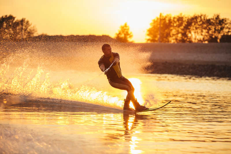 日落阳光下男子在湖面滑水冲浪