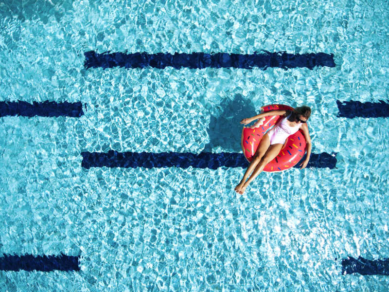 女人躺在游泳圈里在游泳池放松