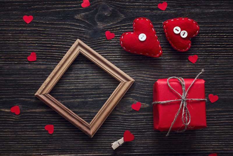 木制背景上的红色爱心礼品盒和相框