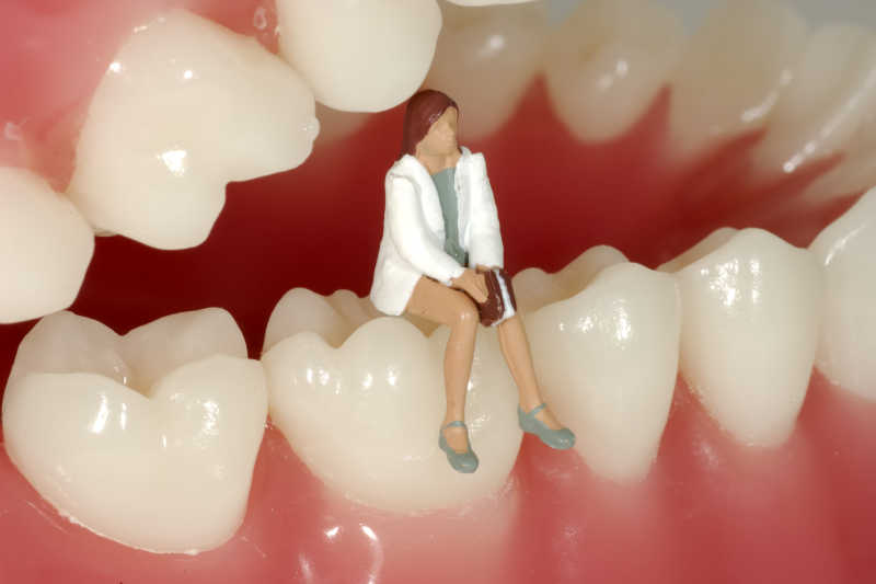 坐在牙齿模型上的小型牙医生