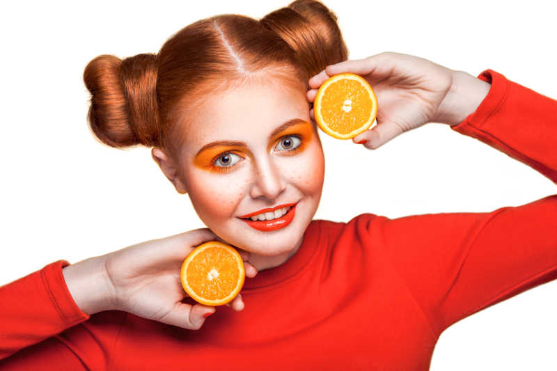 手拿橙子画着橙色妆容的少女