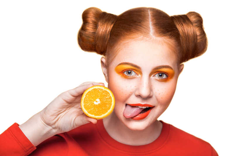 橙色系妆容的拿着橙子的调皮女孩