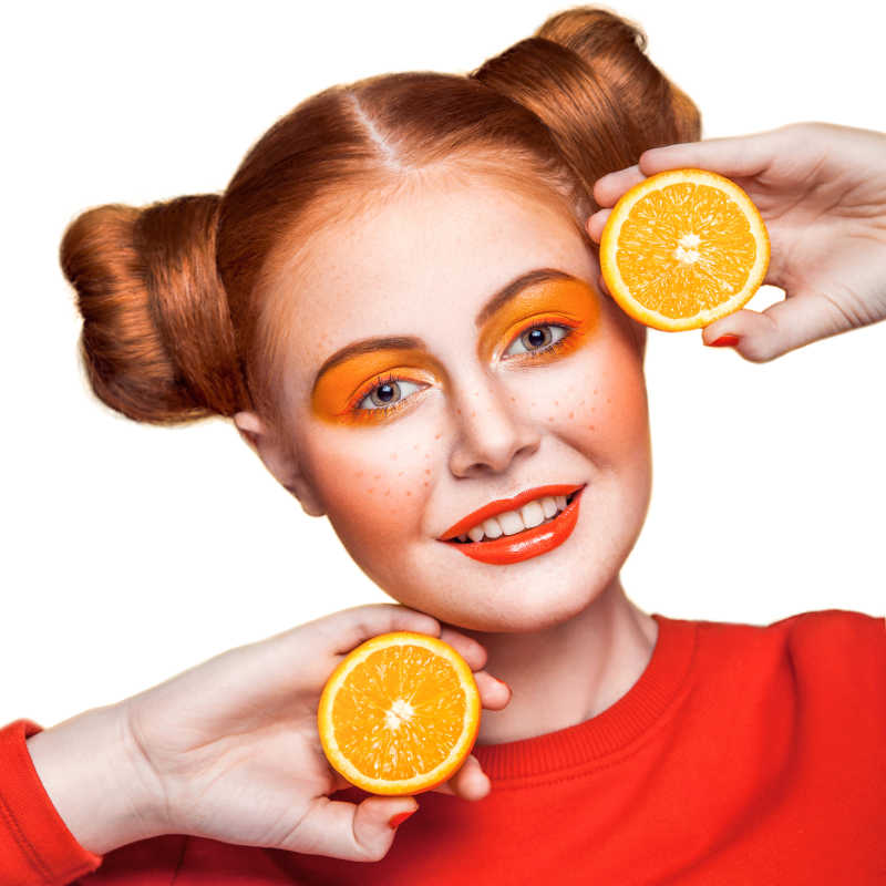橙色妆容手拿橙子的美丽少女