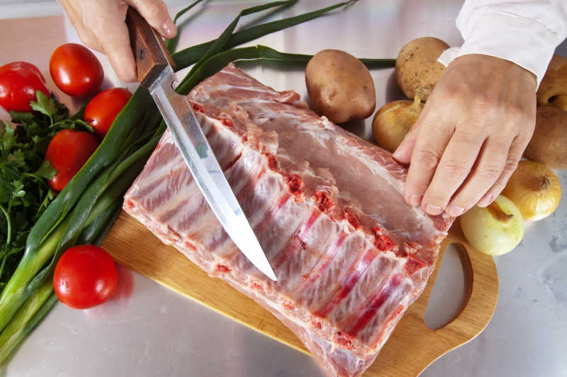 手拿刀准备切生猪肉的特写