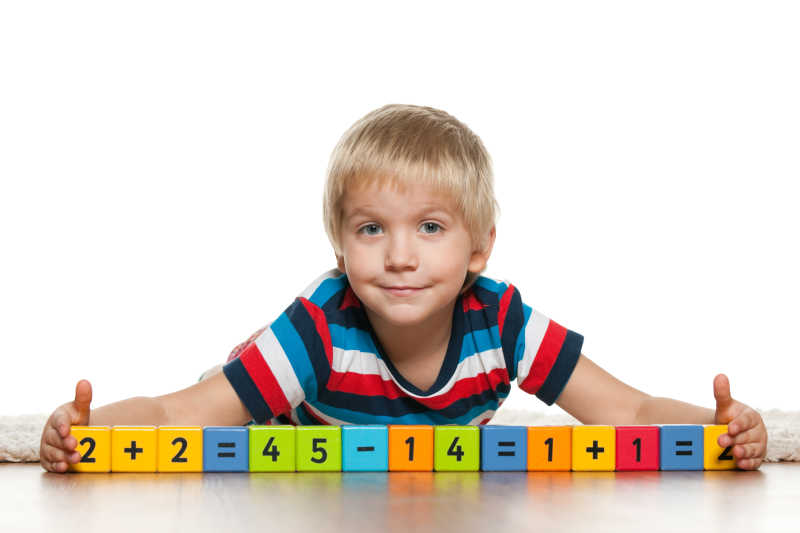 一个聪明的学龄前男孩在地板上玩数字积木