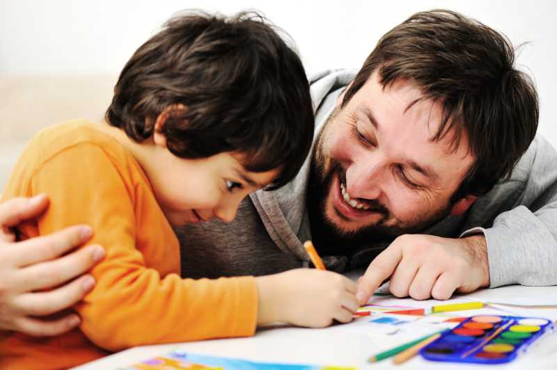 父亲笑着教自己的儿子绘画
