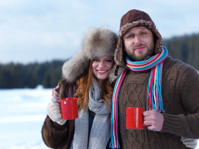 快乐的年轻夫妇在冬天户外喝热茶