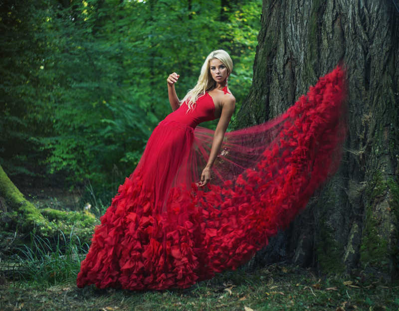 森林里美丽的金发美女穿着红色礼服