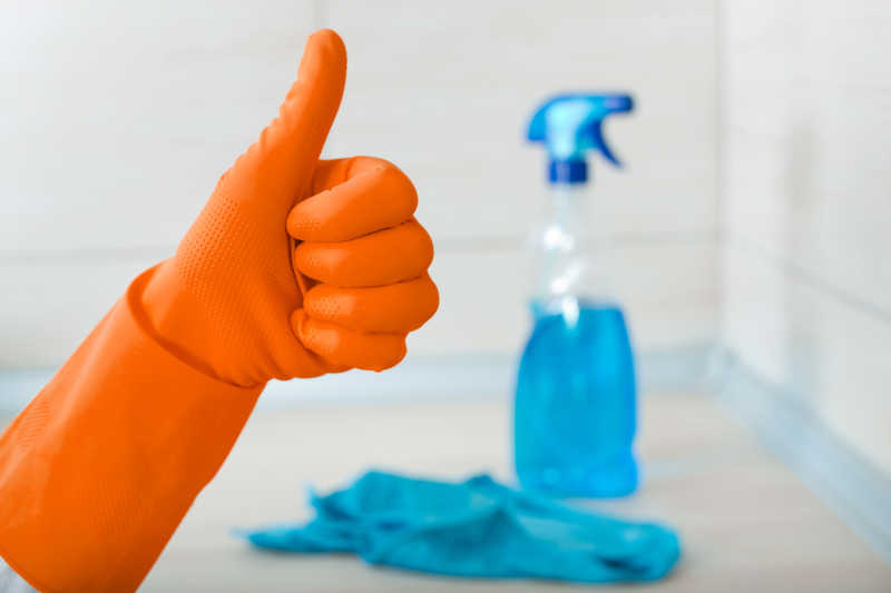 戴着橙色手套竖起大拇指还有一瓶清洗剂