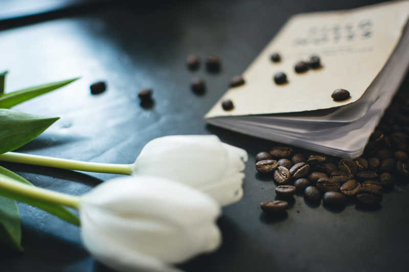 桌上的白色花和咖啡豆书本