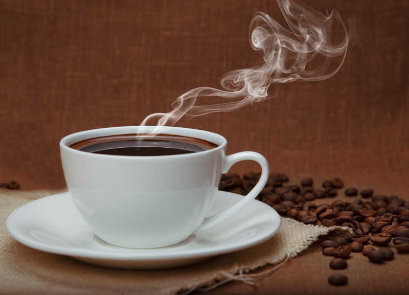 亚麻布上的热咖啡和咖啡豆