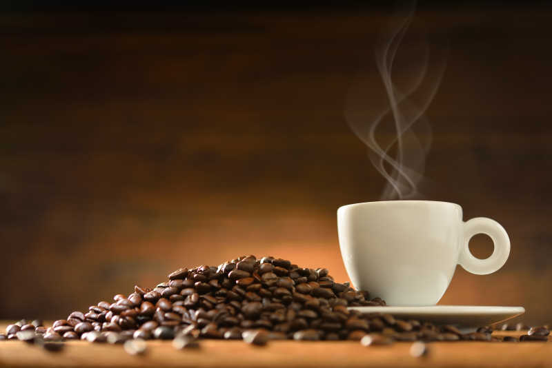 木制背景下的热咖啡和咖啡豆侧面特写