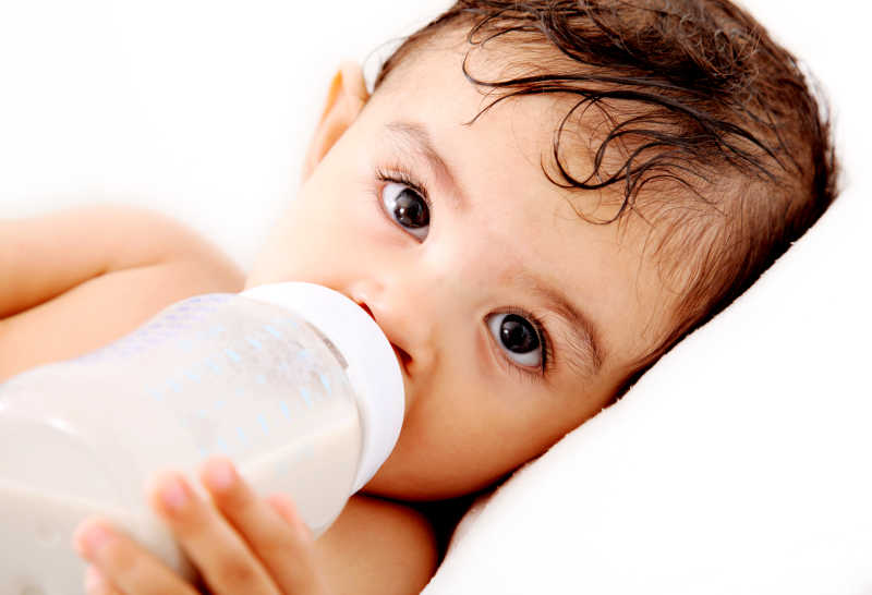婴儿拿着奶瓶喝着奶粉特写
