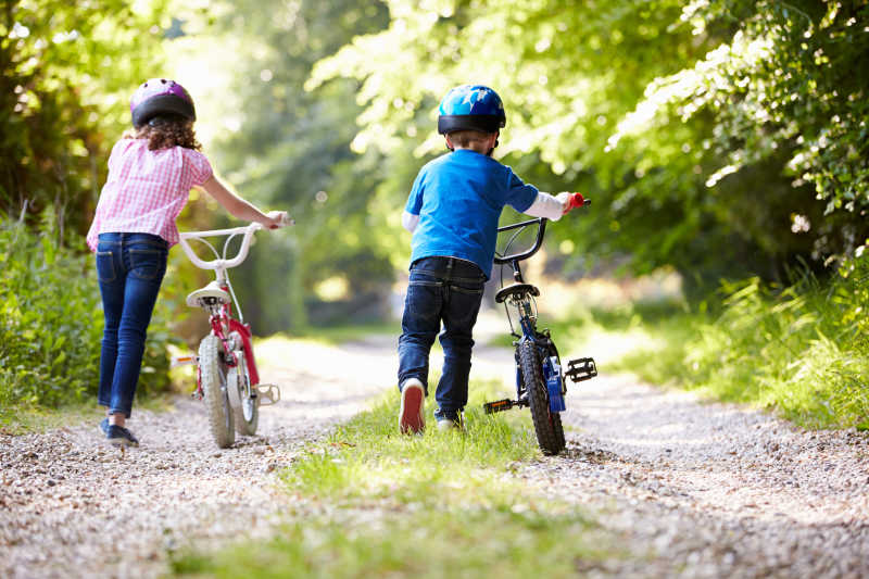 两个孩子在乡间跑道上推自行车