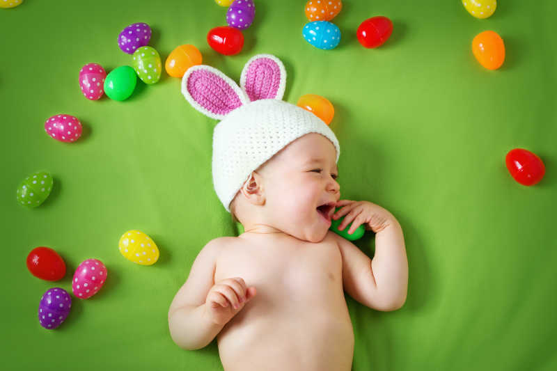 放复活节彩蛋的绿色毛毯上的可爱小男孩