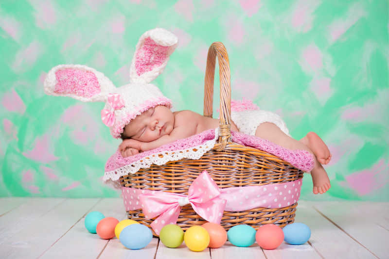 趴在篮子上睡觉的小宝宝和复活节彩蛋