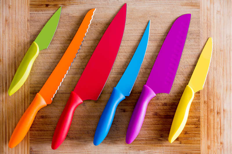 木质砧板上不同用途的彩色菜刀