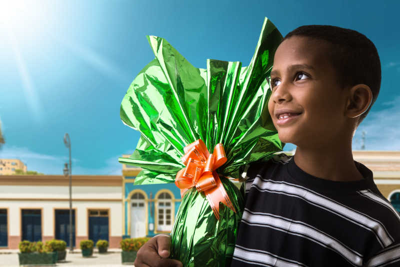 快乐的巴西男孩抱着包装好的复活节彩蛋