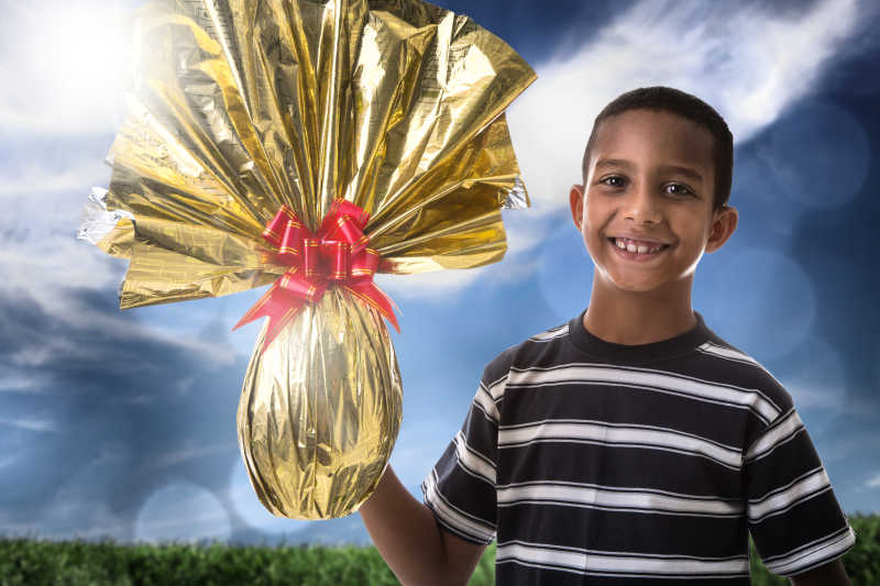 穿着黑白条纹的快乐巴西男孩展示复活节彩蛋