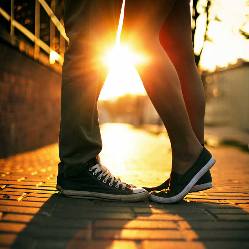 年轻夫妇在夏日阳光下亲吻腿脚特写