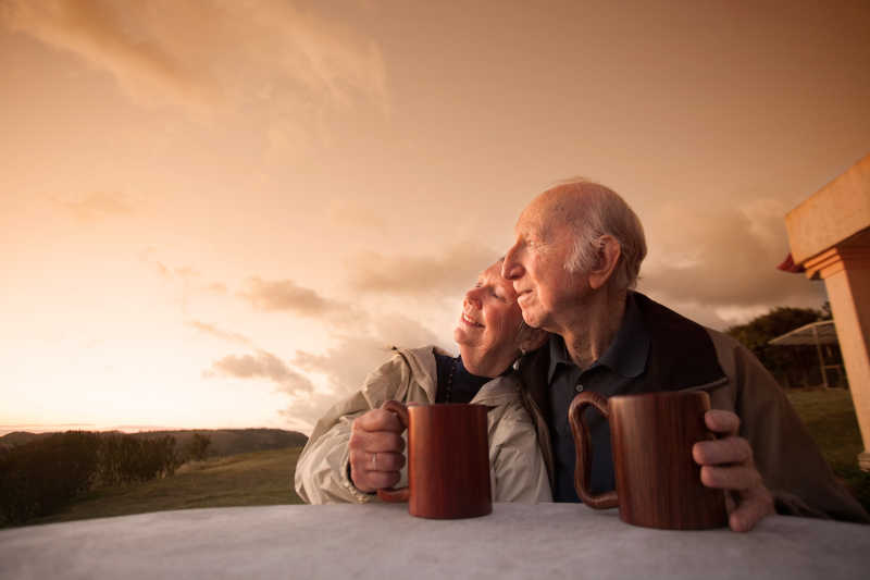 日落时分坐在外面的微笑的老夫妇